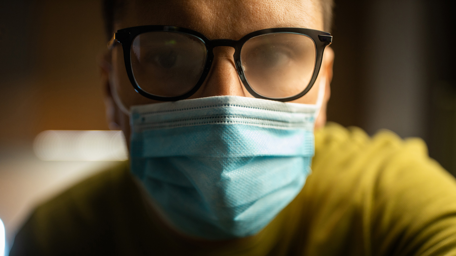 Person wearing protective mask and glasses with foggy lenses.