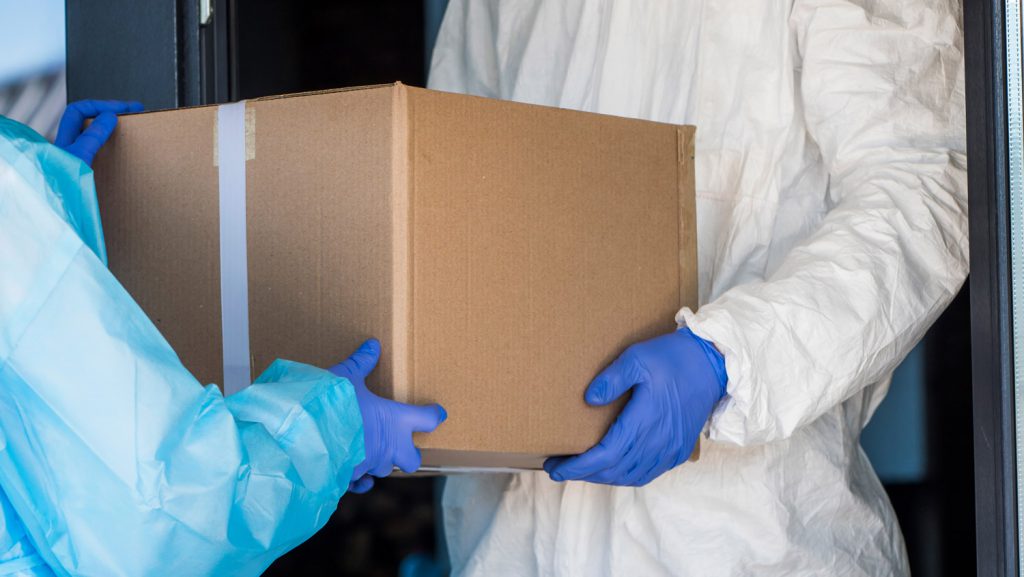 Workers in PPE delivering box.