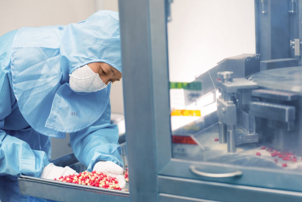 Technician sorts pills at a pharmaceutical factory.
