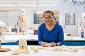 Dr. Phoebe Stubblefield stands in her lab by a table with a human bones.