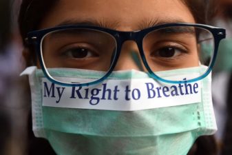Woman with dark hair wearing eye glasses and a mask that reads "my right to breathe."
