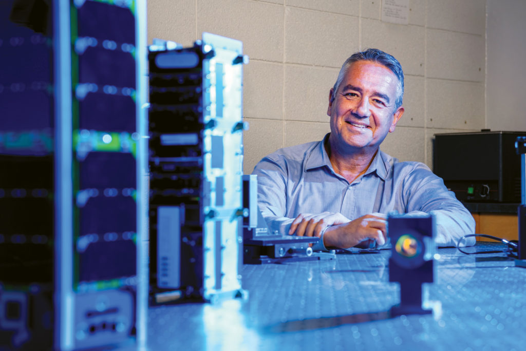 UF astronomy professor Rafael Guzmán at a table with tiny satellites