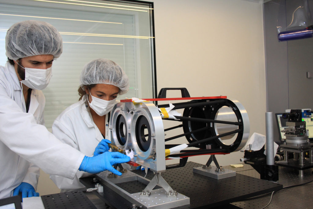 Satlantis team members make adjustments to a binocular camera in the lab.