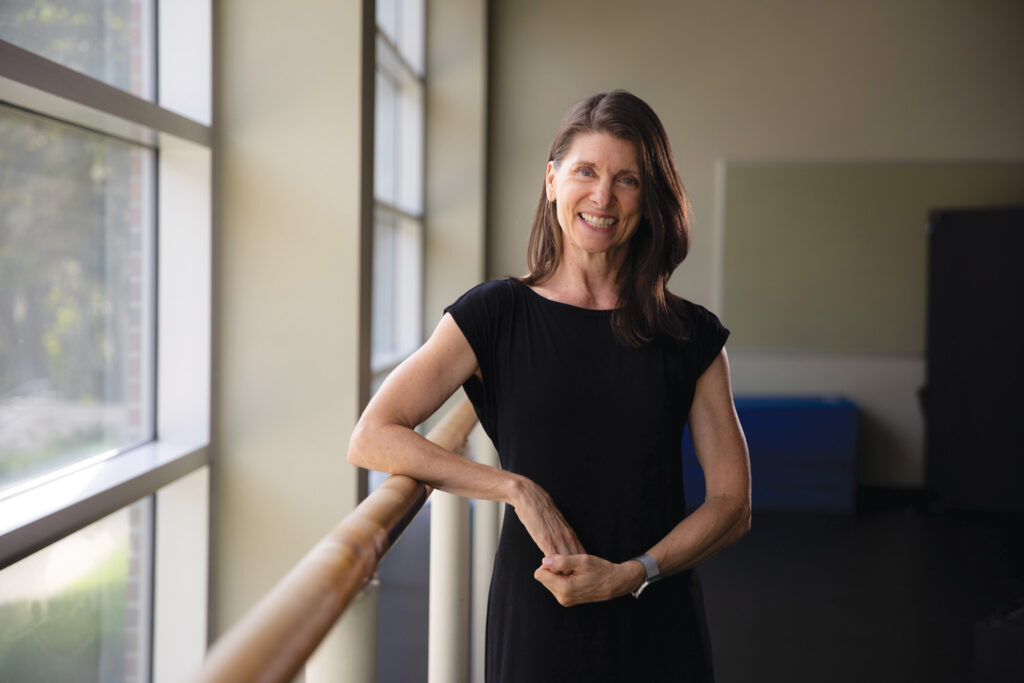 Jill Sonke leaning on ballet barre in a dance studio.