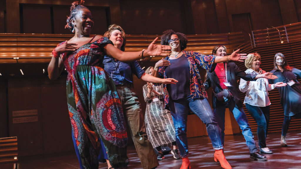 Onye Ozuzu dances in the middle of group of participants on stage at the Creating Healthy Communities Convening.