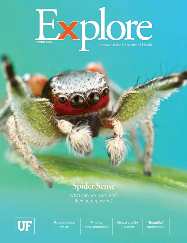 Cover art of Explore Spring 2023 issue depicting a jumping spider with bright red and green hair standing with front arms raised on a green leaf.