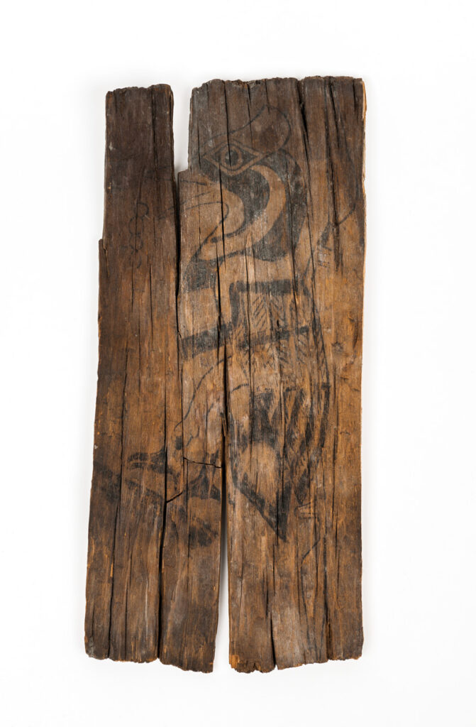 Close-up image of a 1,200-year-old cypress plaque portraying an ivory-billed woodpecker against a white background.