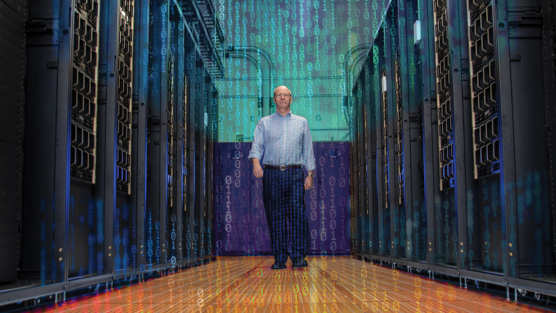 Erik Deumens walks down the aisle of server towers inside UF's Hi-Per Gator Super Computer