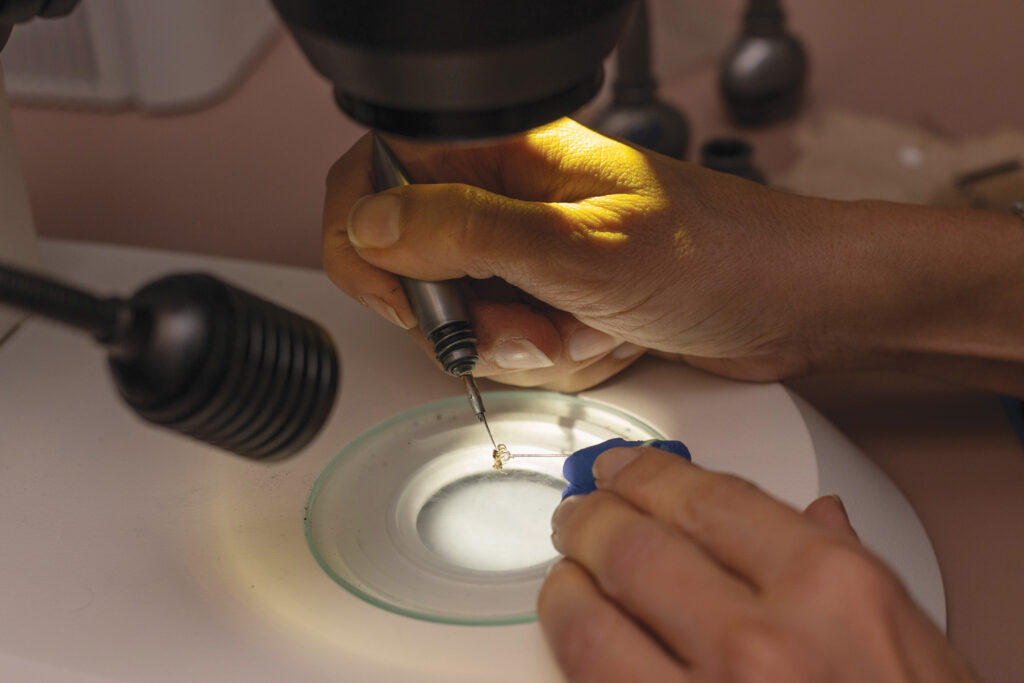 Close-up image of Lisa Taylor using a paint brush to apply hypoallergenic makeup to disguise a spider's coloration under a microscope.