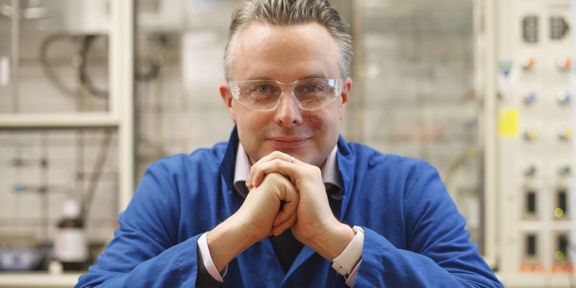 Portrait of Matt Disney sitting in a lab with his chin resting on his clasped hands.