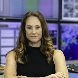 A photo of Jennifer Bridge in front of several computer screens.