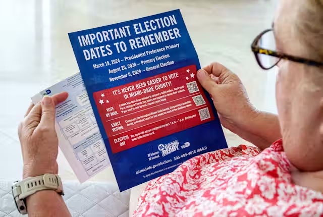 A photo of a person holding a flyer with important dates to remember about the election.